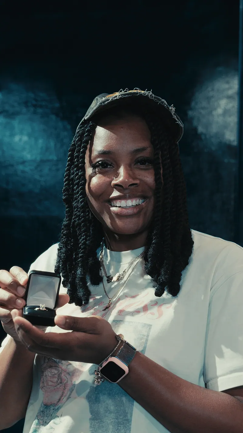A smiling client holding her open jewelry box from The House of Royal T