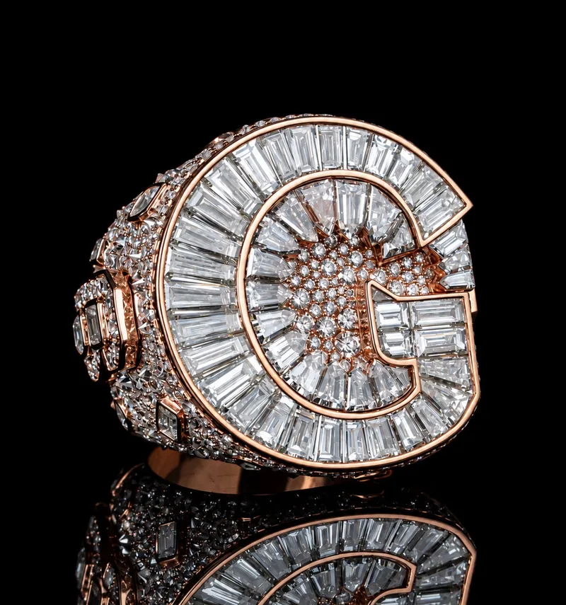 Rose-tone ring with a baguette-set letter G on top