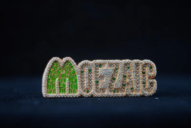Stone-set MOEZAIC lettering pendant with a green M