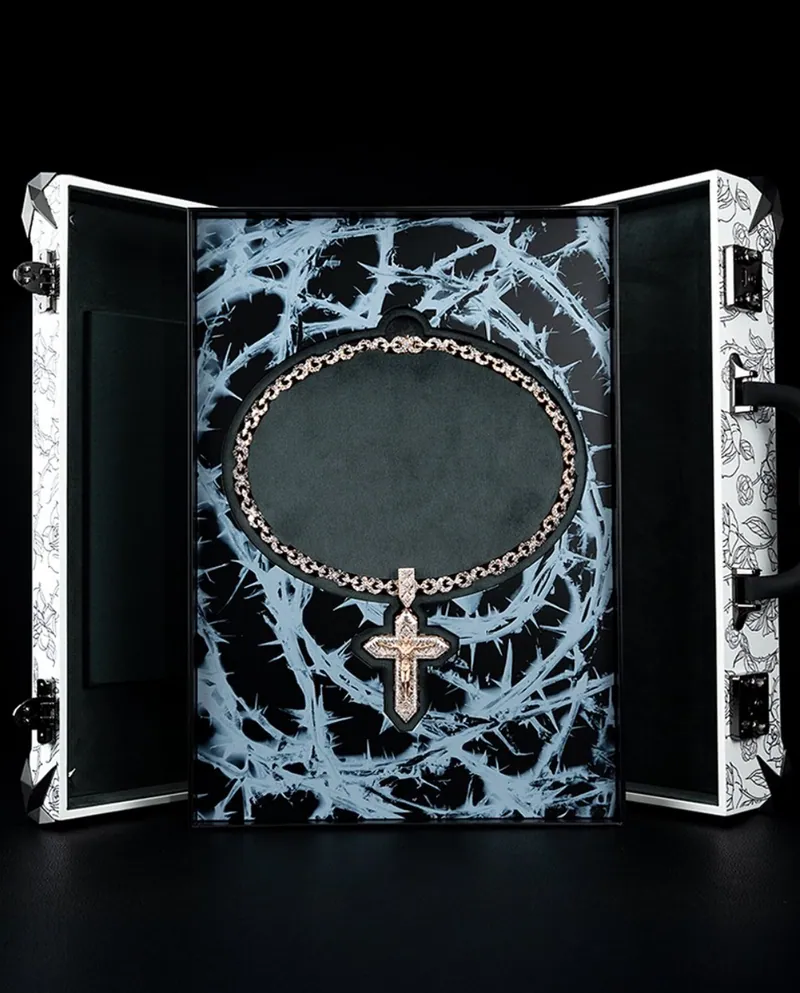 Rose-tone chain with a cross displayed in an open custom case with a thorn-pattern lining