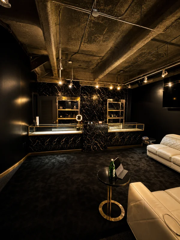 Glass display cases on black marble with brass shelving, beside the lounge seating