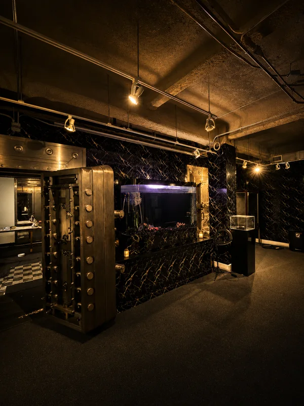 The open vault door beside a lit aquarium set into black marble